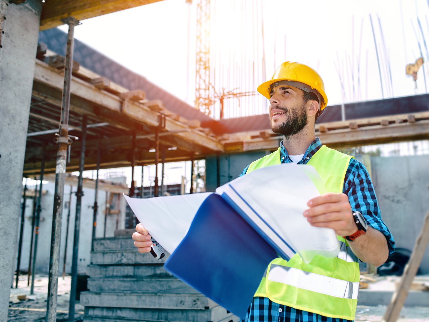 A site engineer reading drawings at a building under construction