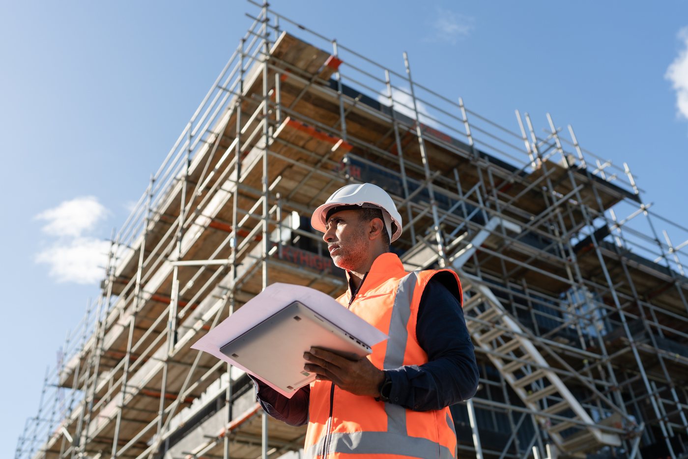 An inspector with drawings in front of scaffolding
