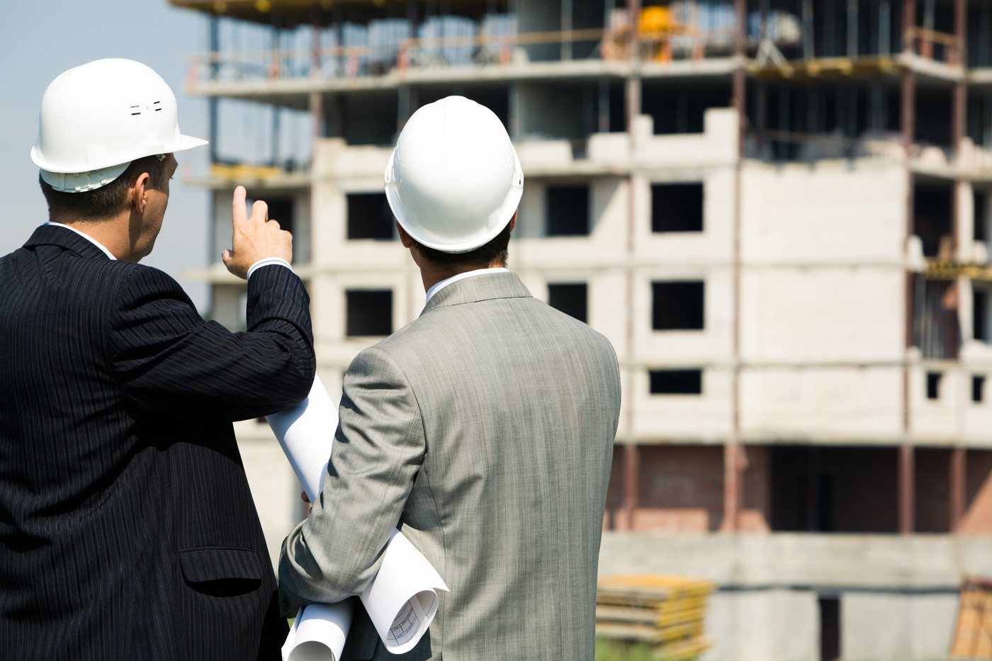 Two people in hard hats reviewing a building under construction