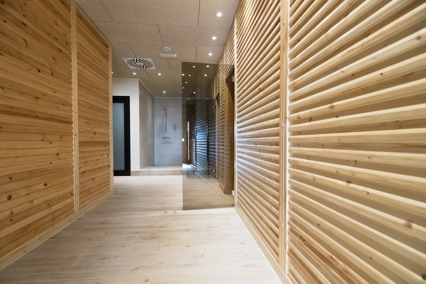 A corridor lined with vertical wood slats leading to a glazed door