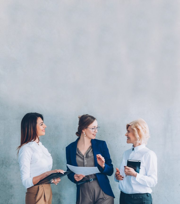 Three professionals talking in front of a concrete wall