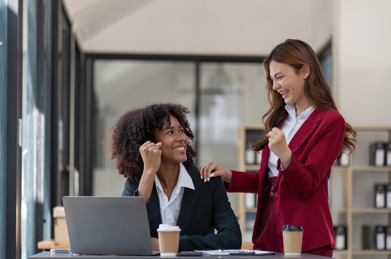Two colleagues at a laptop sharing good news